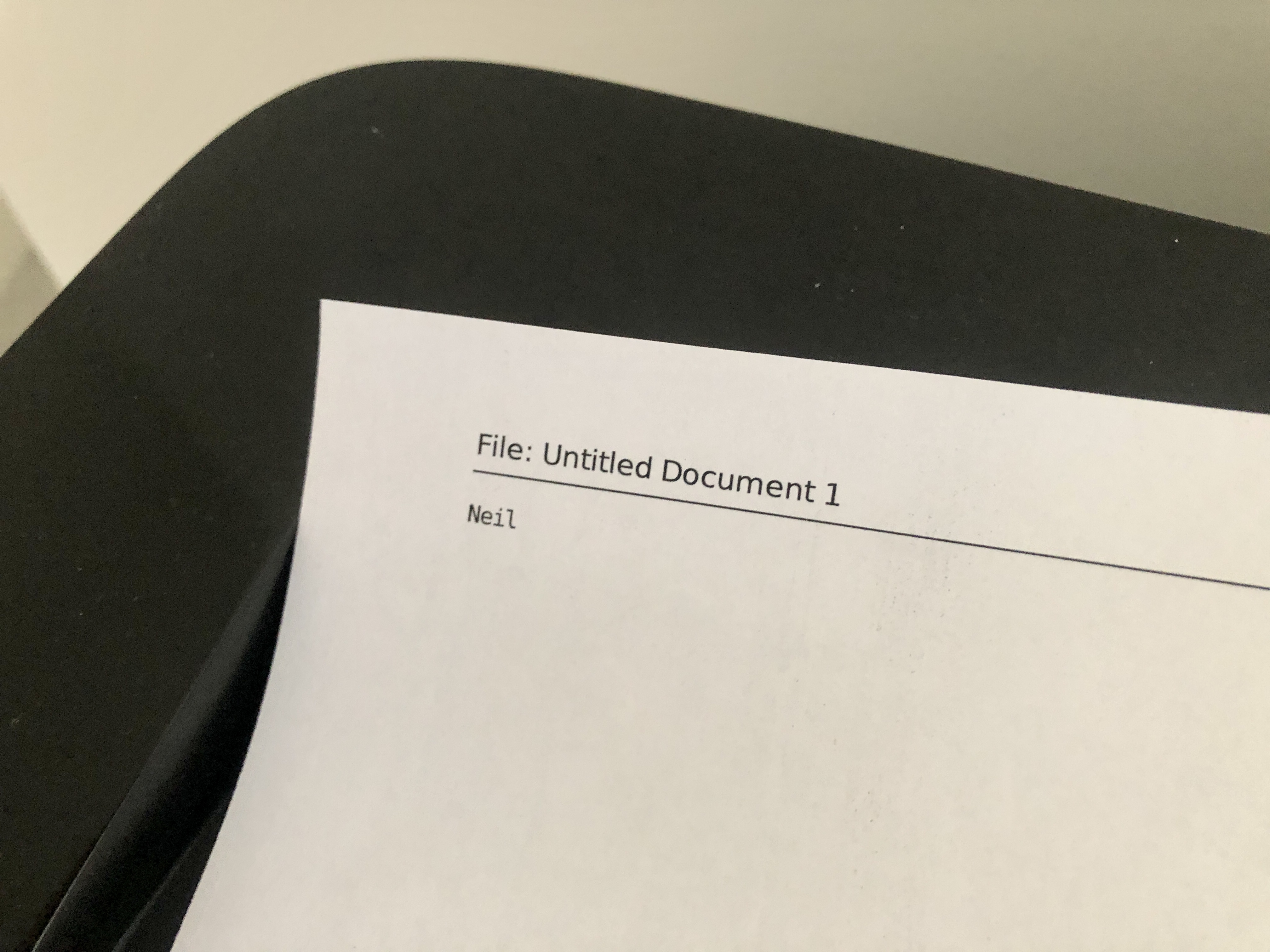 Photo of a sheet of paper on a printer, saying "Neil"