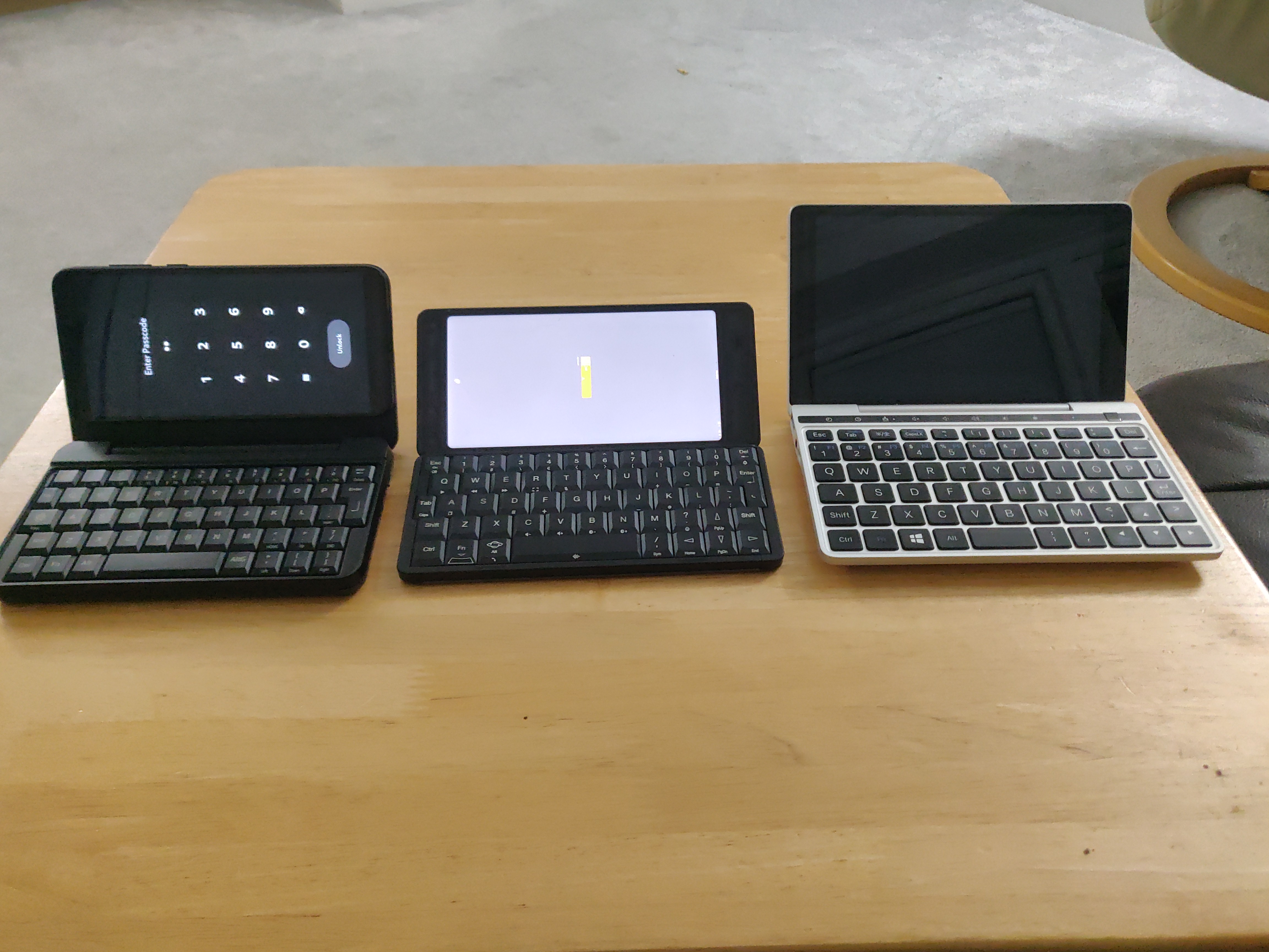 Photo showing PinePhone Pro in keyboard case, next to Planet Gemini, next to GPD Pocket 2, all open