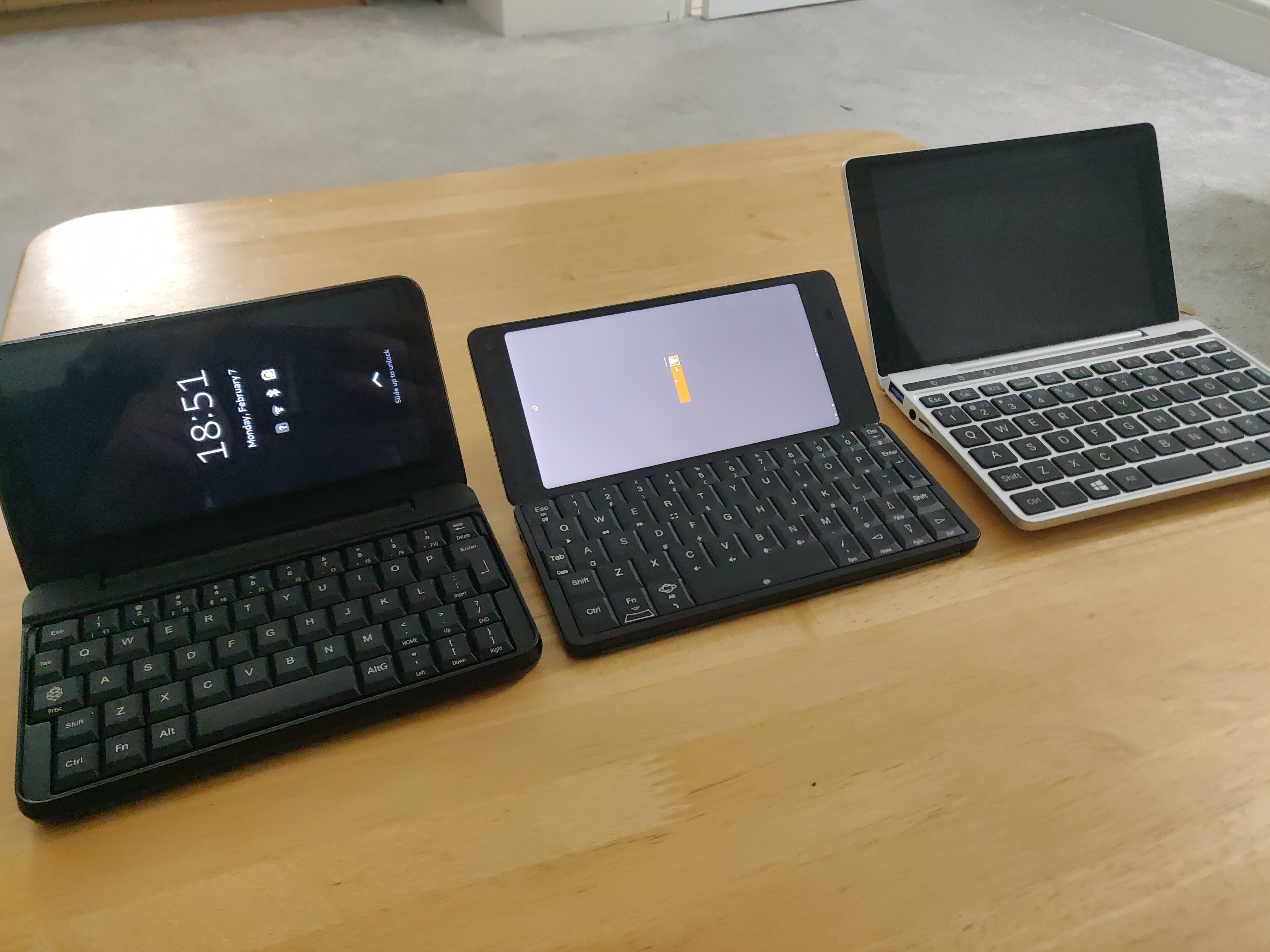 Photo showing PinePhone Pro in keyboard case, next to Planet Gemini, next to GPD Pocket 2, all open