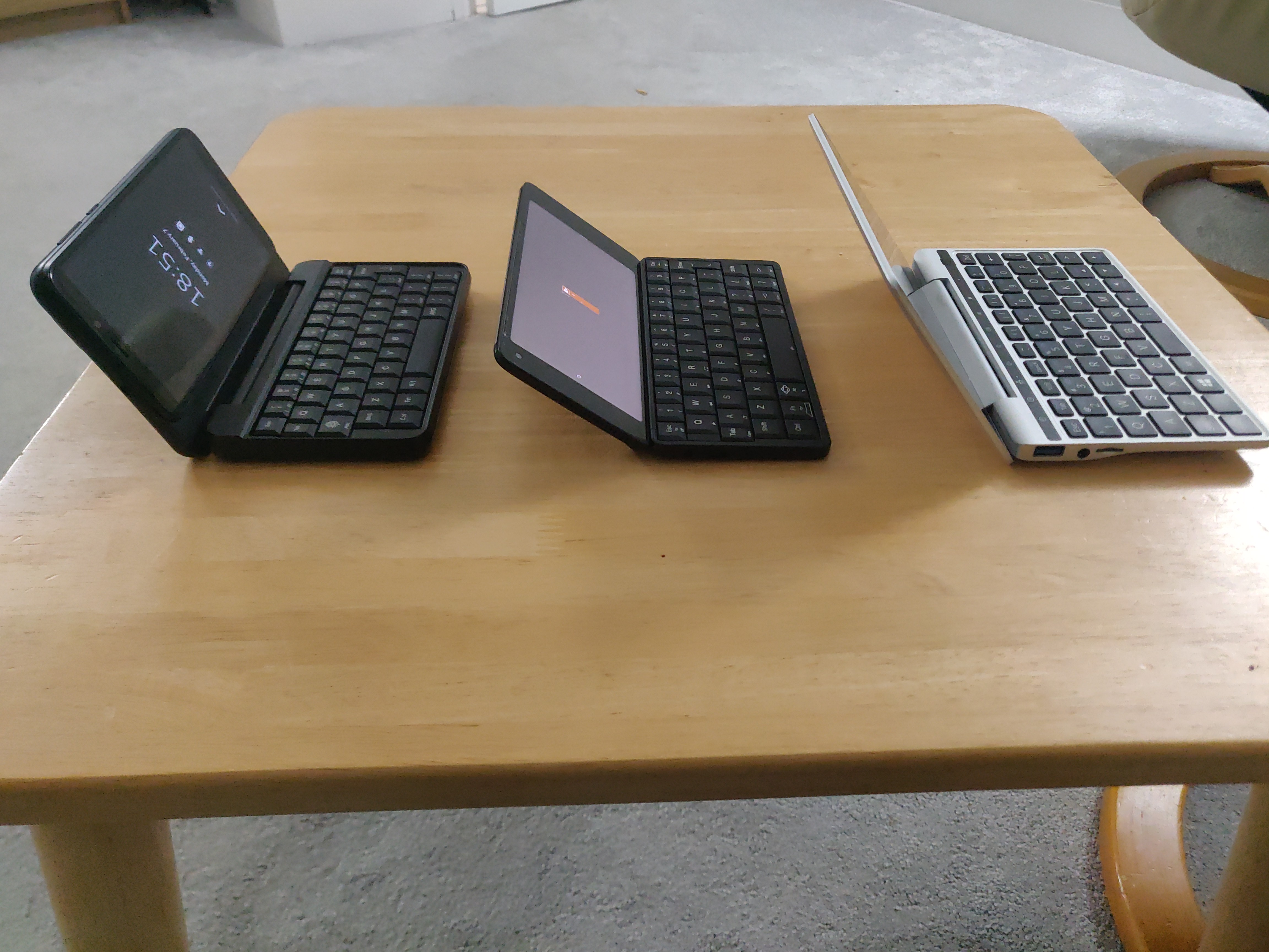 Photo showing PinePhone Pro in keyboard case, next to Planet Gemini, next to GPD Pocket 2, side on