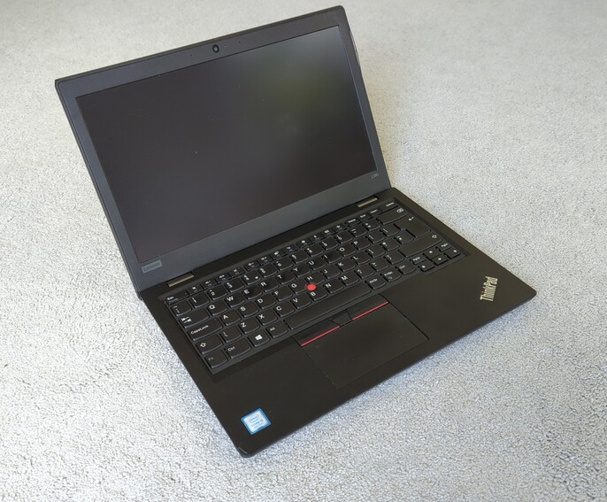 A  black ThinkPad L380, on grey carpet. It is not switched on. It looks to be in good condition