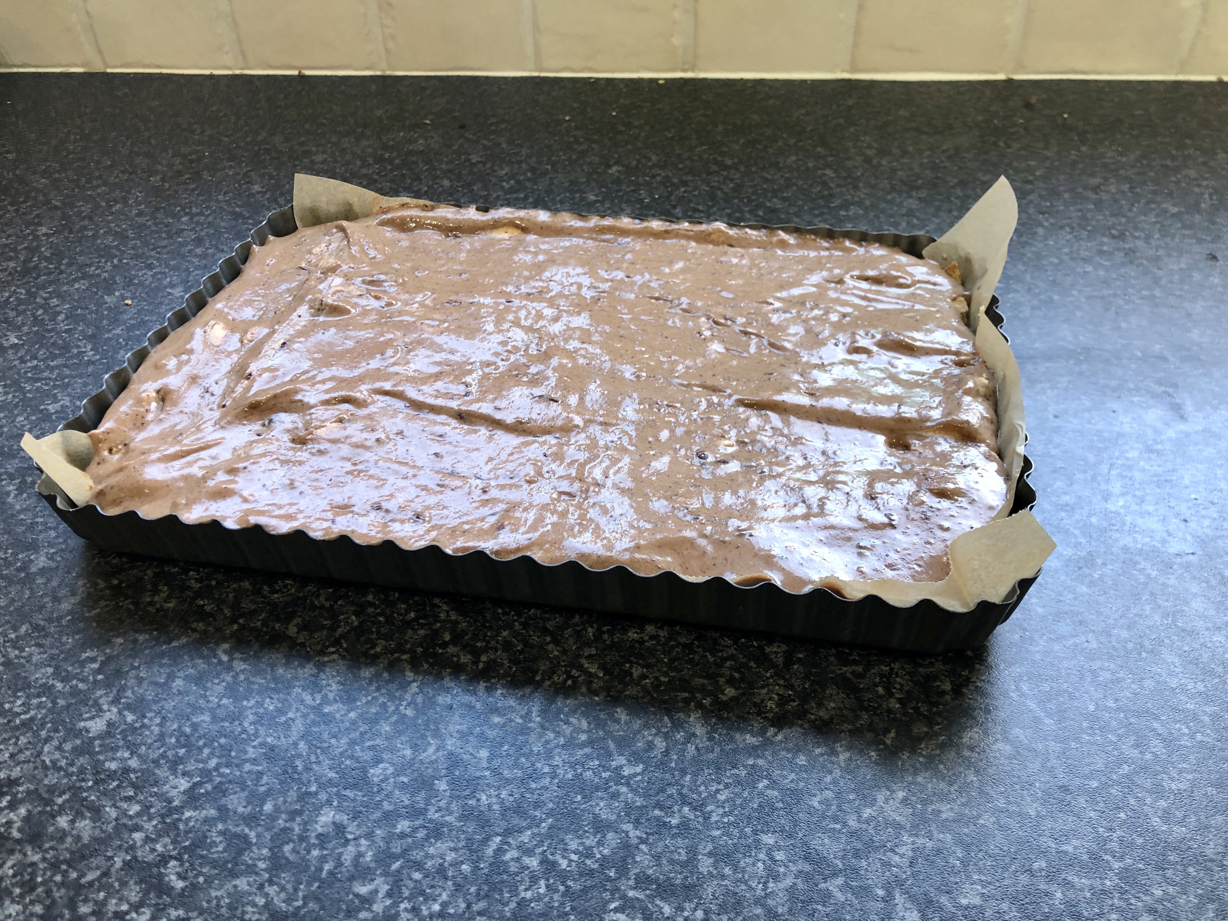 Chocolate cheesecake in a rectangular tin on a kitchen worktop
